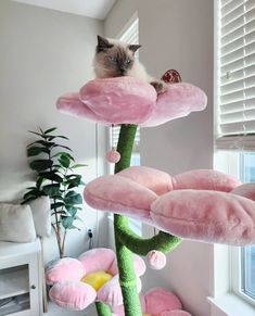 a cat sitting on top of a pink flower shaped tree with lots of stuffed animals hanging from it's branches