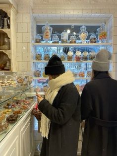 two people are looking at pastries in a glass case behind them is a bakery