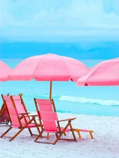 two beach chairs with pink umbrellas on the beach