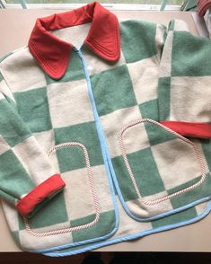 a green and white checkered jacket sitting on top of a table next to a window