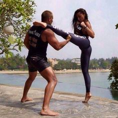 a man and woman are practicing martial moves by the water