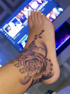 a woman's arm with a rose tattoo on it and a cross in the middle