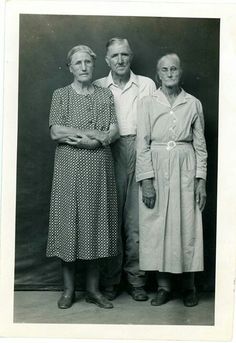 an old black and white photo of three people standing next to each other with their arms crossed