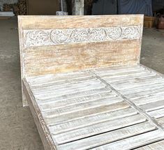 an old wooden bed with white paint on the headboard and foot board, sitting in a warehouse