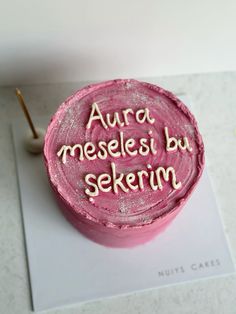 a pink cake with writing on it sitting on top of a table