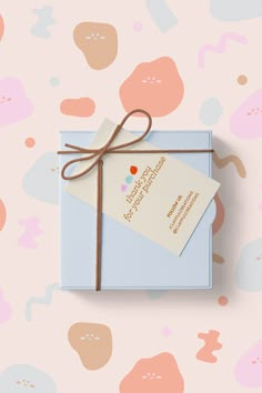 a blue box with a brown ribbon tied around it on top of a pink background