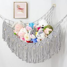 a hammock filled with stuffed animals on top of a white floor next to a wall