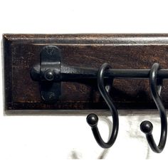 a pair of black metal hooks on a wooden coat rack with two coats hanging from it's sides