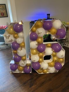 the number six is made out of balloons and gold, white, and purple balls