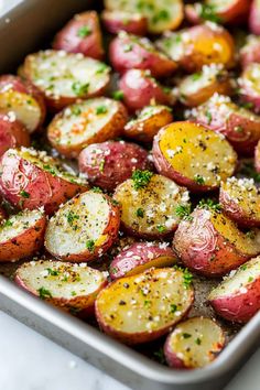 a pan filled with potatoes covered in seasoning and sprinkled with parsley