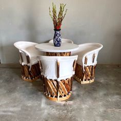 three chairs and a table made out of bamboo sticks, with a vase on top