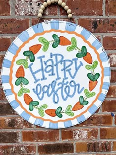 a happy easter sign on a brick wall with carrots and leaves painted on it