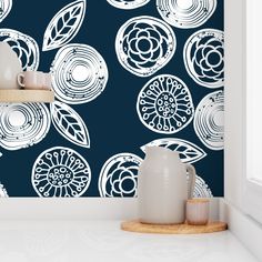 a blue wallpaper with white flowers on it in a kitchen, next to two vases