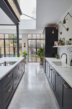 a large kitchen with black cabinets and white counter tops, along with a skylight