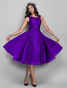 a woman in a purple dress is posing for the camera with her hands on her hips