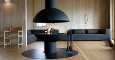 a living room with wood floors and a large black stove in the middle of it