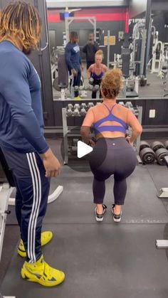 two people in a gym doing squats with one person on the ground looking at another