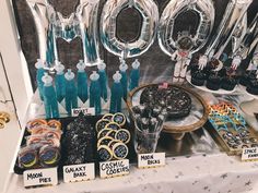 a table topped with lots of desserts next to balloon shaped letters that spell out mom