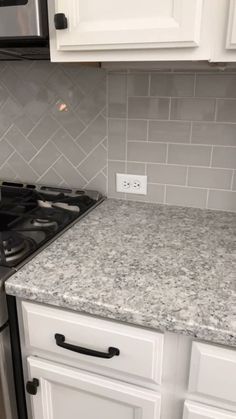 a stove top oven sitting inside of a kitchen next to white cupboards and a microwave