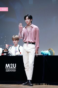 a man standing on top of a wooden floor in front of a screen holding his hand up