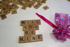 scrabble tiles spelling out the words will you be mine next to a pink bow