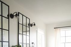 a bath room with a toilet a sink and some mirrors on the wall next to a window