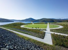 an aerial view of a circular walkway in the middle of a grassy area next to a body of water