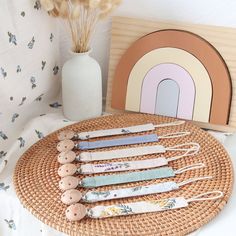 a wicker tray with buttons on it next to a white vase filled with dried flowers