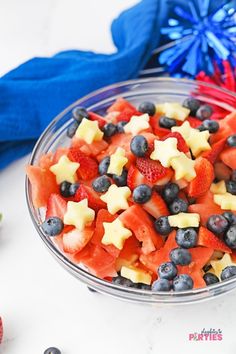 a bowl filled with fruit sitting on top of a table next to apples and blueberries