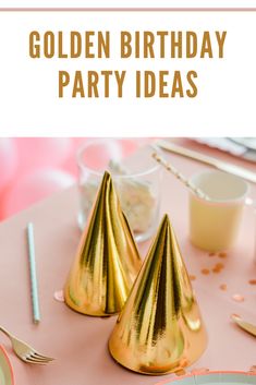 two gold birthday party hats on a pink table with confetti and champagne glasses