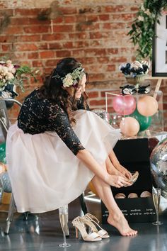 a woman sitting on top of a chair in front of a cake box and shoes