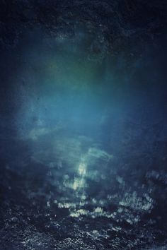 an underwater view of the ocean with dark blue water and light shining on the surface