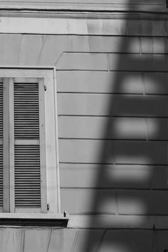 a black and white photo of a window with shutters on the side of a house