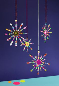 three brightly colored ornaments hanging from strings on a blue tablecloth with polka dot circles