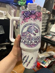 someone holding up a cup with the words motherhood on it