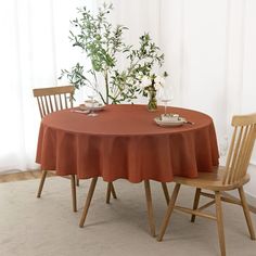 the table is set with two wooden chairs and a red cloth on it, along with a vase filled with flowers