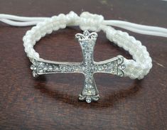 "Beautiful thick nylon cord metal rhinestone cross bracelet. With a square knot pattern .  This bracelet is adjustable with a pull closure. Ends will dangle slightly . Thick intricate  rhinestone cross as the center focal.  Cross measures  Bracelet goes from 7\" to 9\"  1 3/8\" long 1 1/2 \" wide I do ship world wide . Please message me for a quote if you don't see your shipping ." Adjustable Cross Pendant Jewelry, White Adjustable Cross-shaped Jewelry, Adjustable Cross Jewelry With Cord, Adjustable Cross Jewelry With Adjustable Cord, Adjustable Cross-shaped Jewelry With Cord, Creative Bracelets, Knot Pattern, Square Knot, Rhinestone Cross