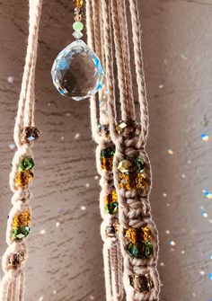 a close up of a wind chime hanging from a wall with beads and chains