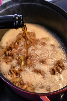 a pot filled with noodles and sauce being poured into it