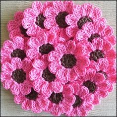 crocheted pink and brown flowers are arranged in the shape of a circle on a white surface