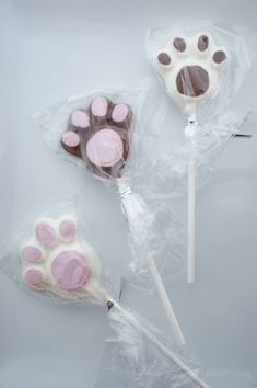 two lollipops with pink and white frosting on them in plastic bags