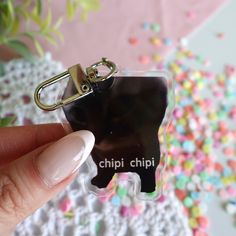 a person holding a keychain with a black cat on it