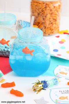 there is a fish bowl with blue liquid in it and some candy on the table