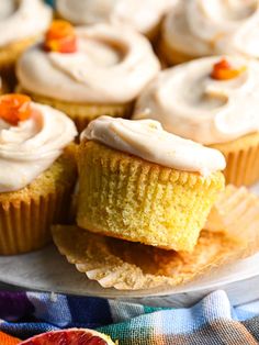 cupcakes with frosting and candies on a plate next to an orange slice