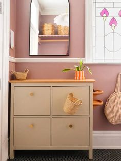 a dresser with baskets on top and a mirror above it in a pink walled room