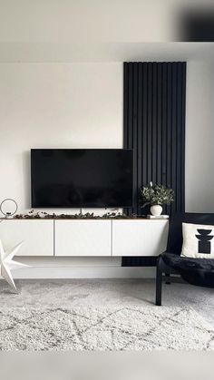 a modern living room with black and white decor, including a flat screen tv on the wall