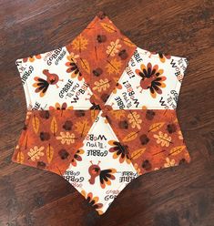 an orange and white flowered umbrella sitting on top of a wooden table next to a wood floor