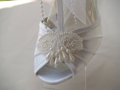 a pair of white shoes with pearls and bows on the heels are hanging from a string