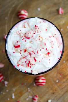 a cup filled with whipped cream and candy canes on top of a wooden table