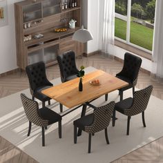 a dining room table with black chairs and an open bookcase in the background is a large window